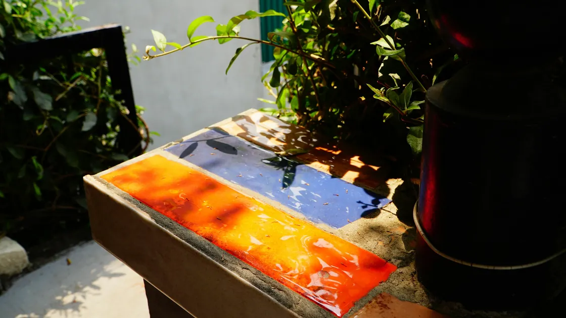 Piezas planas de vidrio de colores dispuestas sobre una superficie de trabajo antes de montar una placa para fusing